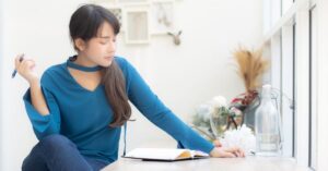 Woman sitting by a window and writing in a notebook, used as the featured image for a free word counter article.