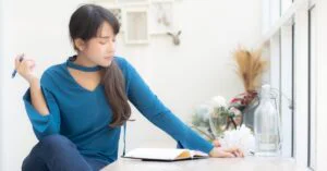 Woman sitting by a window and writing in a notebook, used as the featured image for a free word counter article.