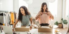 Two small business owners packing product boxes beside a laptop in a bright retail workspace, representing Canadian SMEs preparing orders while exploring business tools and AI adoption.