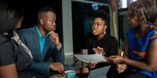 Persuasive Techniques That Close Deals (And Why They Work) Four business professionals discussing a document during a meeting, with a laptop and coffee on the table.