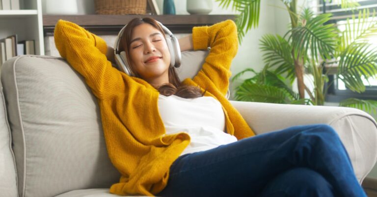 Person relaxing on a couch while listening to headphones with a device that may use microSD storage