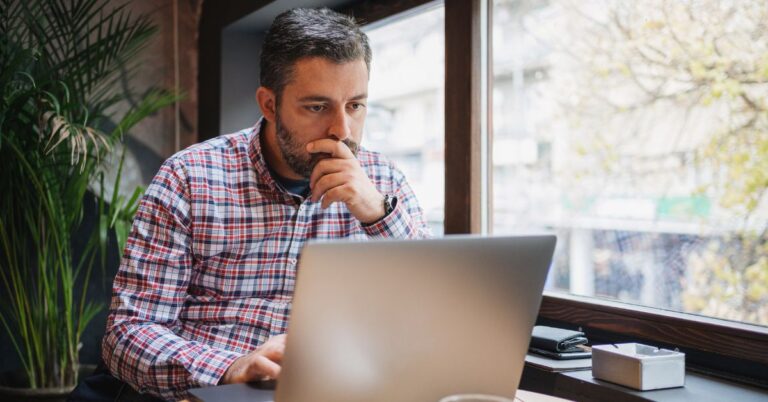 Business owner looking at a laptop, representing how Google AI Overviews may affect buying searches, website traffic, and online visibility.