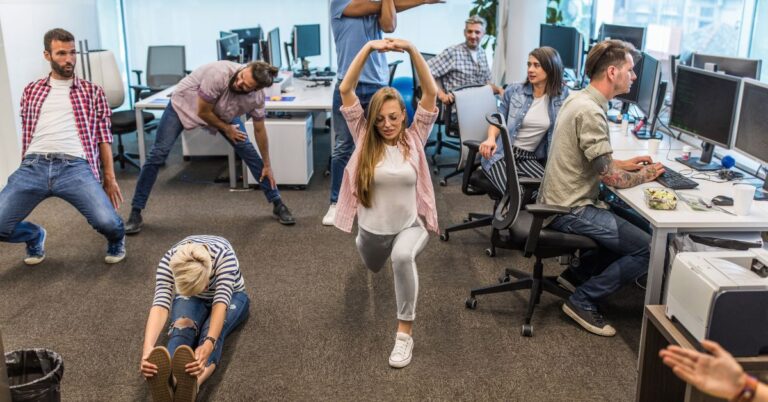 Office workers stretching and moving at their desks during a workplace wellness break.