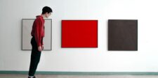Person viewing bold red artwork in a minimalist gallery, representing brand differentiation and standing out
