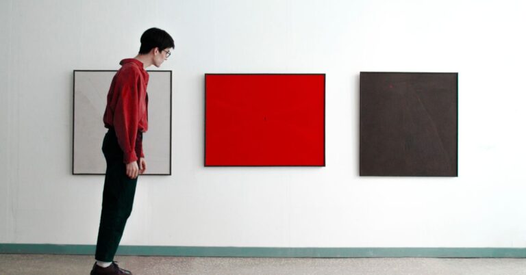 Person viewing bold red artwork in a minimalist gallery, representing brand differentiation and standing out