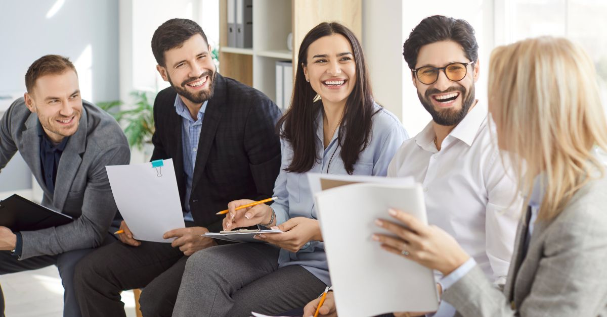 Business professionals smiling during a team discussion in a bright office setting.