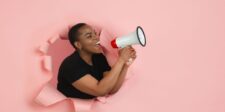 Meta and Google Are Firing You From Your Own Ad Campaigns Person speaking through a megaphone against a pink background, representing digital advertising and marketing automation.