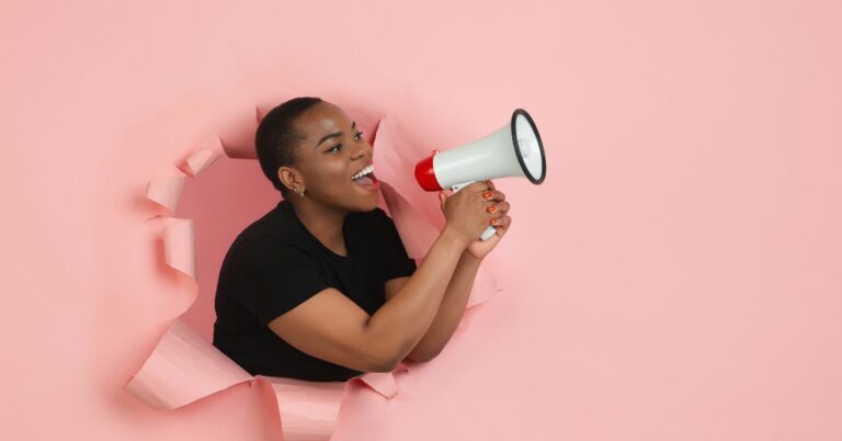 Person speaking through a megaphone against a pink background, representing digital advertising and marketing automation.