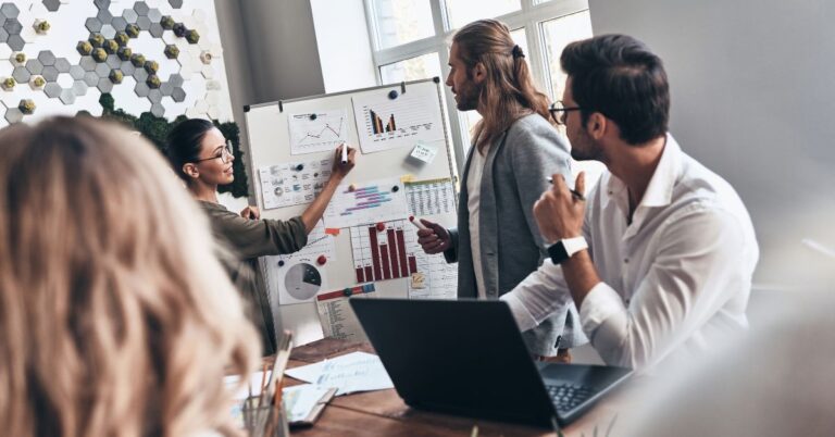 Microsoft 365 pricing article image showing a small business team reviewing charts and planning software costs in a meeting.