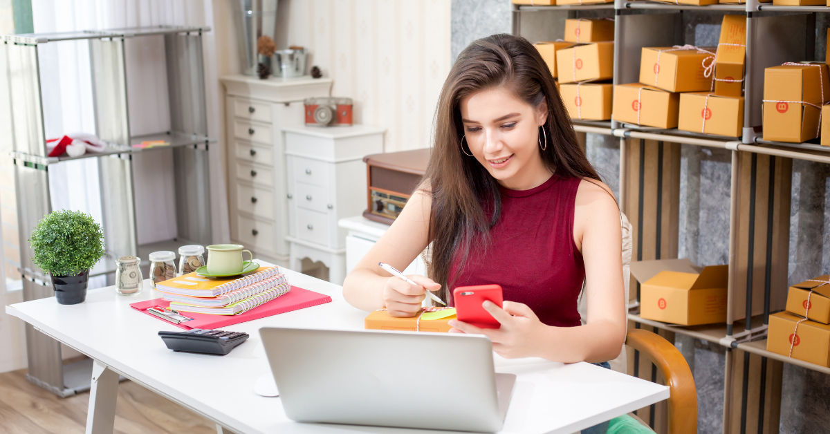 Small business owner working on orders with a laptop and phone, representing professional email and Microsoft 365 tools for business.