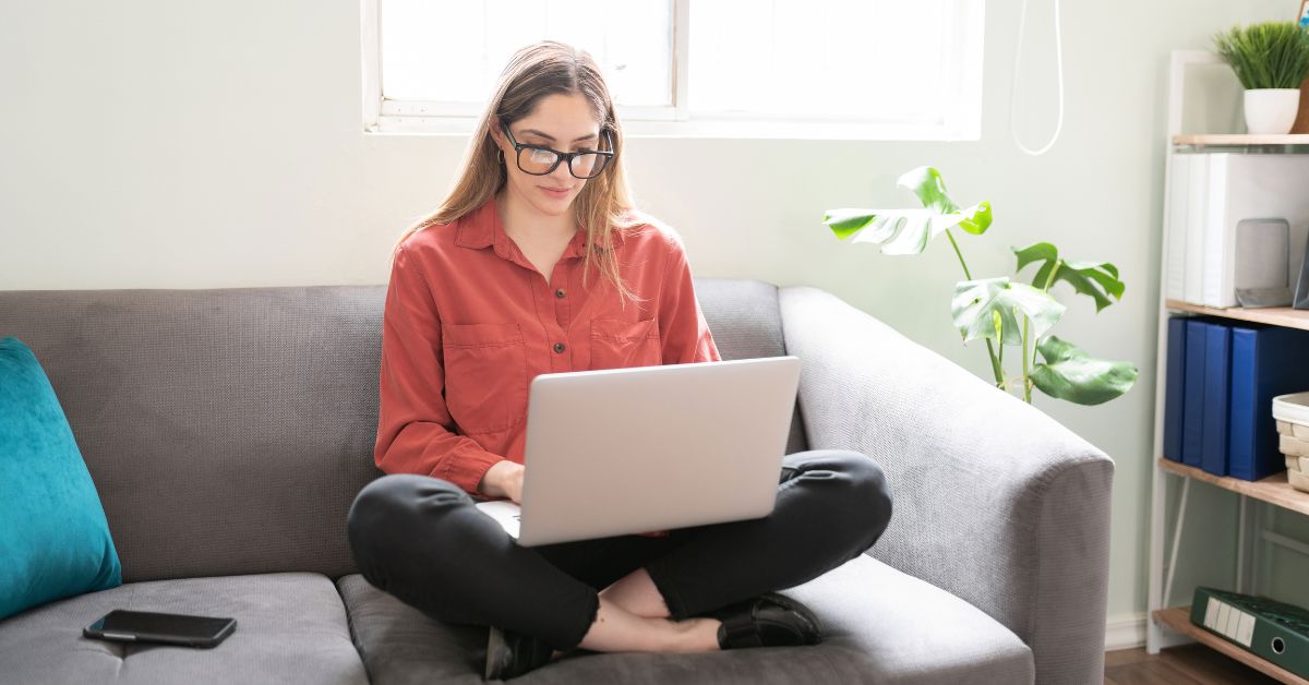 Person using a laptop on a couch, representing content optimization and on-page SEO work before publishing.