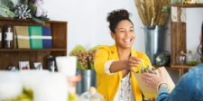 The 12 Customer Types Every Business Sees (Most Only Know How to Sell to 3) Smiling retail worker handing a gift bag to a customer inside a bright boutique shop.