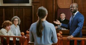 Courtroom scene showing a lawyer speaking before a judge and other people during a legal proceeding.
