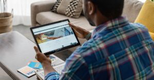 Person using a tablet to view LinkedIn while sitting at home with a laptop nearby.