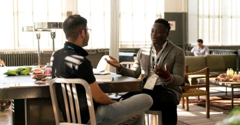 Two professionals having a business conversation in a bright office lounge.