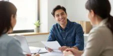 Ontario's small business tax cut takes effect July 1 — but read the fine print Smiling business owner reviewing documents during a meeting with two advisors in a bright office.