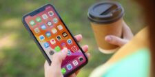 What most people forget before selling their smartphone A person holds an iPhone in one hand and a takeaway coffee cup in the other while using smartphone apps outdoors.
