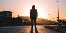 10 boring decisions that can change your life Person in a hooded sweatshirt standing alone in the middle of a road at sunset.