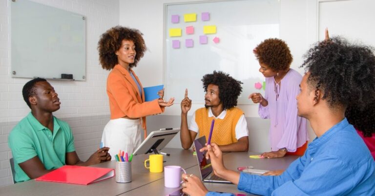 Team discussing ideas in a meeting room with sticky notes on a whiteboard.