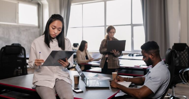 Team members working in an office with laptops and notes, representing business teams preparing for cybersecurity risks.