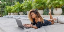 Digital marketing vs affiliate marketing: the data-backed comparison Woman lying on an outdoor lounge chair while working on a laptop.