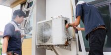 Two technicians working on an outdoor air conditioning unit at a residential property.