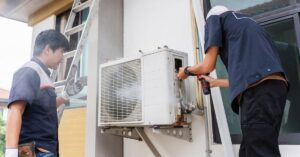 Two technicians working on an outdoor air conditioning unit at a residential property.