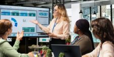 Meta just made ad creation 10x faster & it's a problem Team in a meeting discussing marketing dashboard data displayed on a large screen.