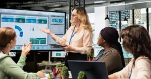 Team in a meeting discussing marketing dashboard data displayed on a large screen.