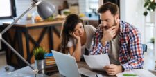 Back-to-school spending forecasts conflict. Value is the clear signal Concerned couple sitting at a table and reviewing documents beside a laptop.