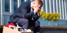 Mark Zuckerberg Says AI Will Create More Jobs—Months After Meta Cut 8,000 Workers Distressed business professional sitting beside a box of office belongings outside a corporate building.