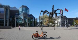 Ottawa cityscape with the Maman spider sculpture and a Canadian flag outside the National Gallery of Canada.