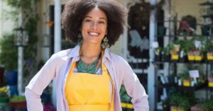 Smiling small business owner standing outside a garden shop.