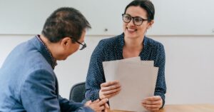 Two business professionals reviewing documents together during a meeting.