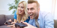 The gaming industry found a new way to make players pay Excited man and woman playing video games together with controllers while sitting on a couch.