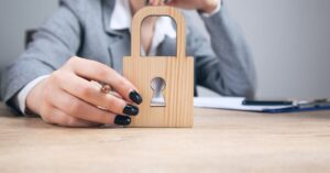 Woman holding a wooden padlock on a desk, representing website security and protection.
