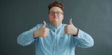 How to price a lifetime deal without losing money Man in glasses giving two thumbs up against a dark background.