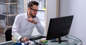 Man working at a desktop computer in an office.
