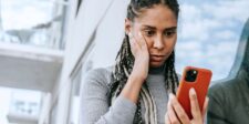 Woman looking concerned while checking something on her smartphone.