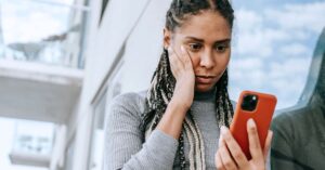 Woman looking concerned while checking something on her smartphone.