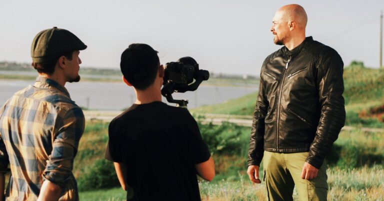 Film crew shooting an outdoor scene with a camera operator and performer on location.