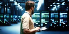 Alibaba’s Zhenwu V900 chip is only one piece of a bigger AI plan Technician working on a laptop inside a large data center with rows of server racks.