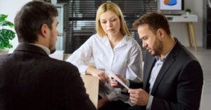Three business professionals reviewing a document together during a meeting.