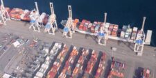 Aerial view of Roberts Bank Superport in British Columbia, showing a container ship, cranes, and rows of shipping containers.