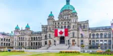 Canada gives billion-dollar investors priority access to tax rulings British Columbia Parliament Buildings in Victoria with a large Canadian flag displayed above the entrance.