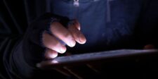 Close-up of a person using a tablet in a dark setting, representing a cybersecurity threat or active exploit.