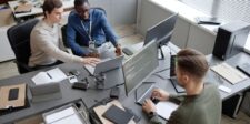 Cybersecurity team reviewing code and system activity across multiple computer screens.