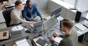 Cybersecurity team reviewing code and system activity across multiple computer screens.