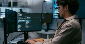 Developer working at a computer with multiple monitors displaying code.