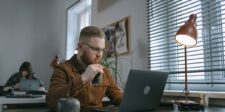 Man working on a laptop in an office while reviewing digital advertising content.
